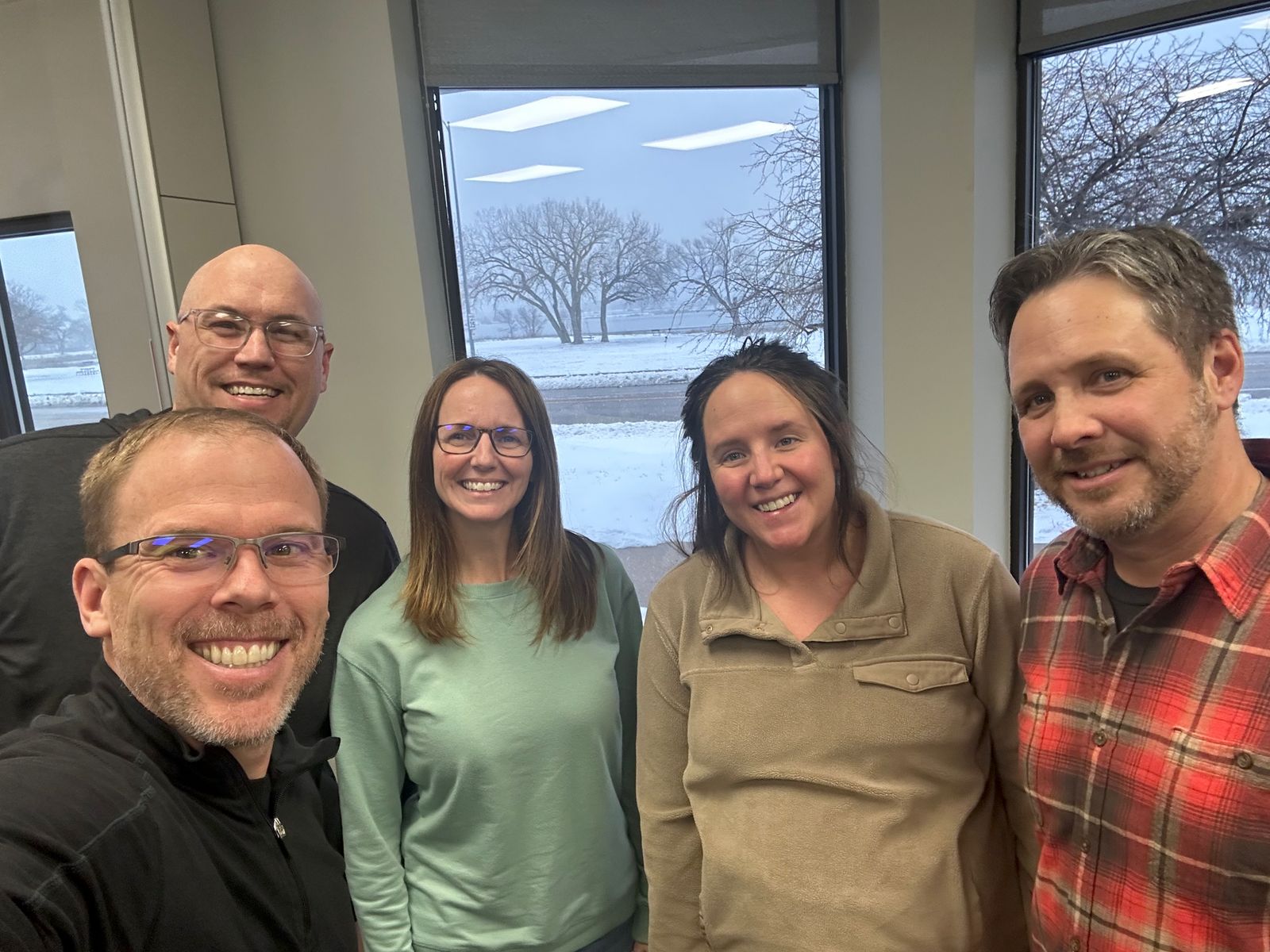 Scott with a client leadership team by a snowy window