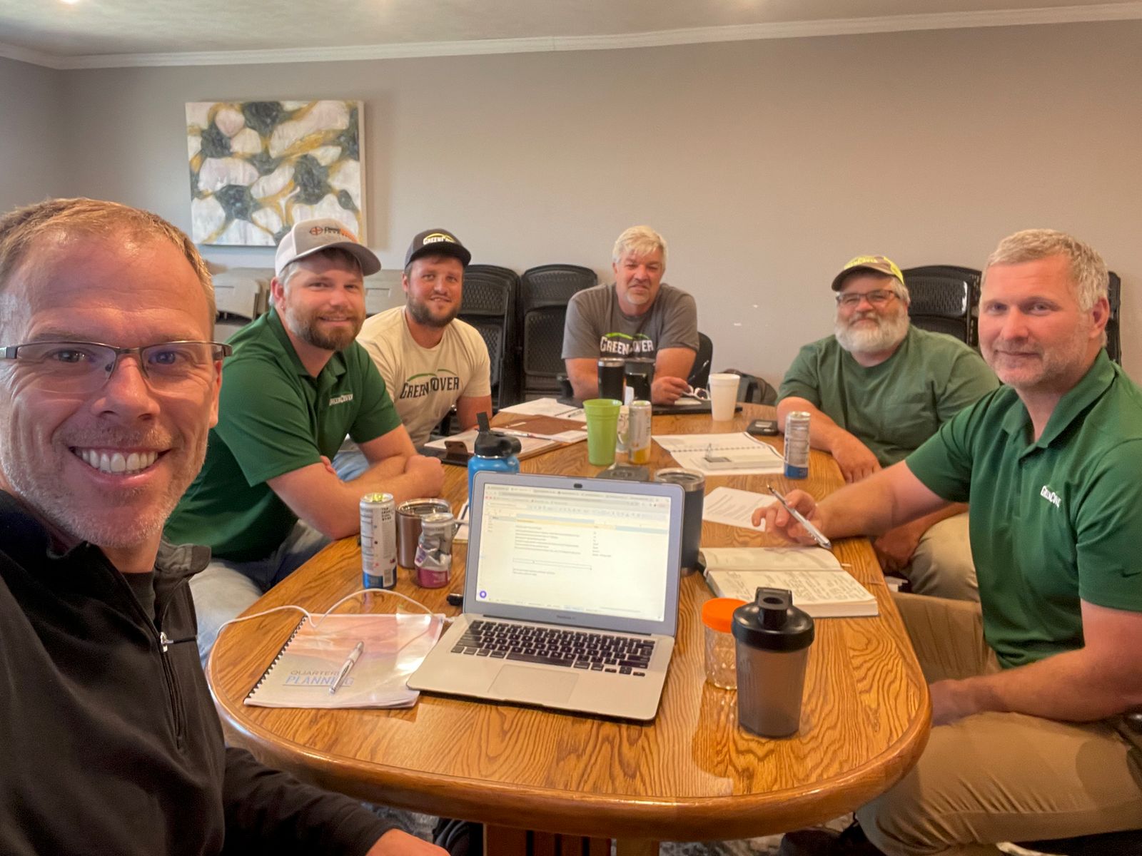 Scott at the table with a client leadership team during a working session, laptop and notes out